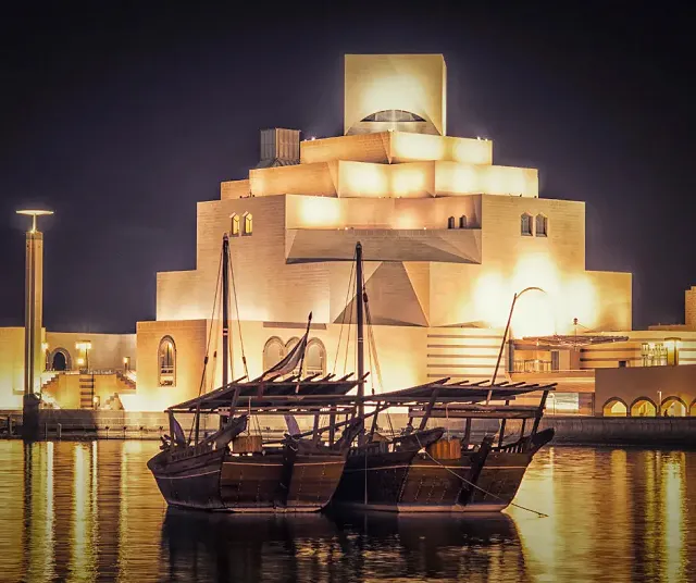 a ship in front a mosque lit up at night in Qatar