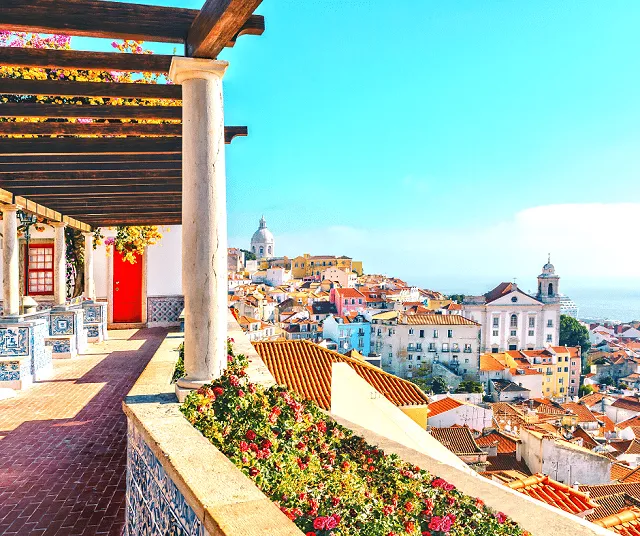 A walkway with ivy over the top with a view across Lisbon in the Alfama district