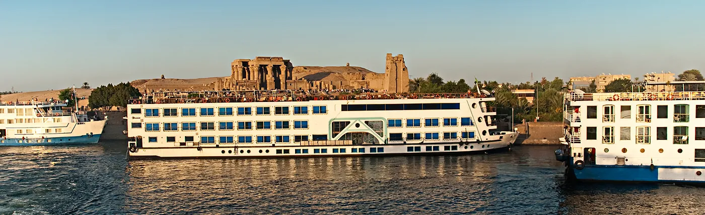 a river cruise ship docked by ruins on the nile